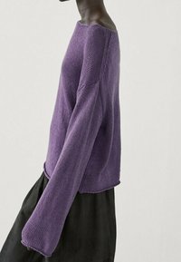 Pull violet en maille avec manches longues évasées, doté d'un large col et d'une coupe décontractée. Matériau texturé avec un design casual.
