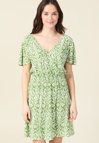 Vestido verde con estampado, hecho de una tela ligera, con escote en V, mangas de volantes y cintura elástica para un ajuste relajado.