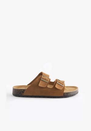 Sandale en suede marron à glissière avec deux boucles en argent réglables, semelle intérieure texturée et semelle en caoutchouc noir moucheté.