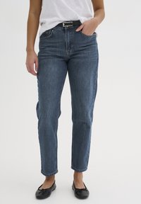 Jeans in denim blu scuro con vestibilità dritta, design classico a cinque tasche e una leggera sfumatura. Abbinati a una cintura nera e scarpe basse.