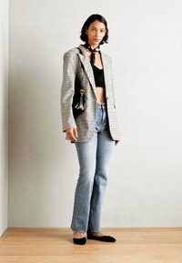 Rutig kavaj i ljusgrått och vitt, svart crop-top, högmidjade jeans, svarta lägenheter och en svart väska. Mjuk textur och strukturerad design.