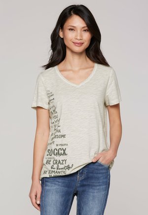 Hellbeige V-Ausschnitt-T-Shirt aus weichem Stoff, mit dunkelgrünen Textmustern und motivierenden Aussagen auf der linken Seite.