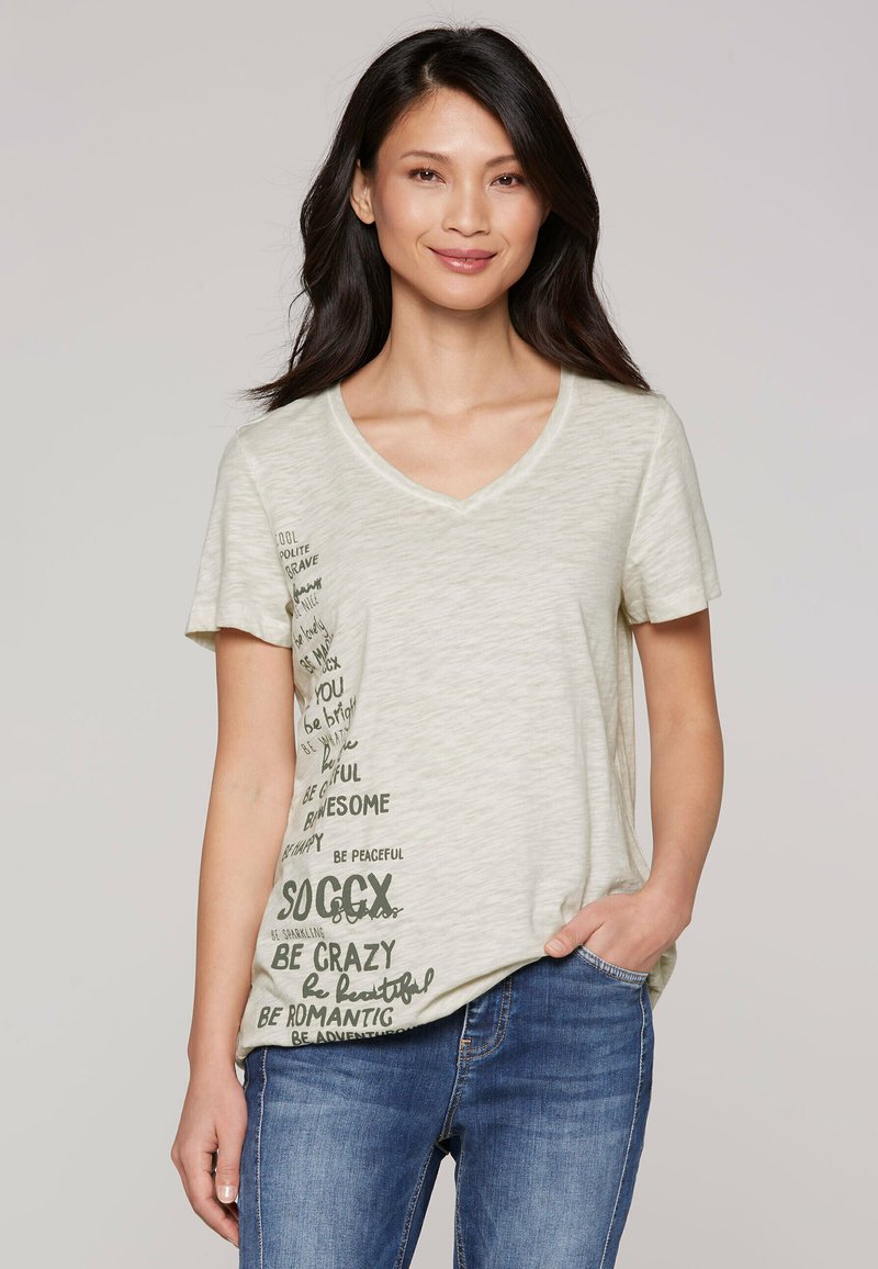 Light beige V-neck t-shirt made of soft fabric, featuring dark green text patterns with motivational phrases on the left side.