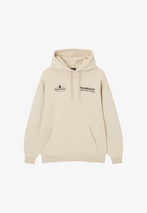 Sudadera beige con capucha, bolsillo delantero, cordones y texto negro que dice "SCARFACE" y "THE WORLD IS YOURS" en el pecho.