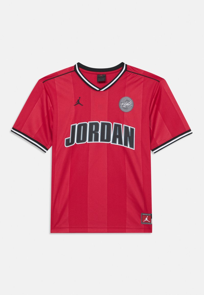 Červený dres s černými akcenty, krátké rukávy, límec ve tvaru V, s nápisem "JORDAN" velkými černými písmeny a kulatou nášivkou.