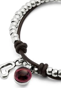 Pulsera de cuero marrón con cuentas de plata, un charm en forma de corazón y una cuenta redonda de vidrio morado. Textura suave con acentos brillantes.