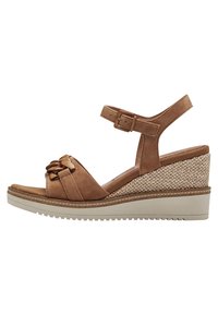 Tan suede wedge sandal featuring a braided accent, ankle strap with buckle, and woven-textured heel. Rubber sole for traction.
