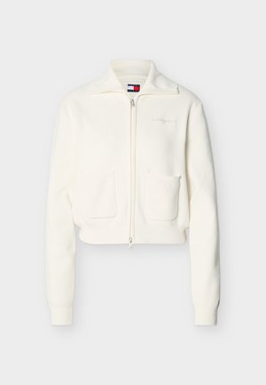 Vit cardigan med dragkedja och två framfickor, ribbade muddar och fåll, samt en diskret broderad logotyp på bröstet.