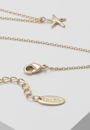 Collier chaîne en or avec un pendentif étoile de mer, fermoir mousqueton et une plaque ovale gravée du nom de la marque Orelia.