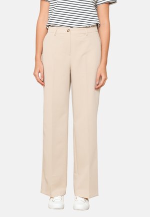 Beige wide-leg trousers with a smooth texture, single button closure, and front pockets, paired with a striped shirt and white sneakers.