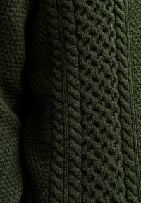 Pull en tricot de couleur vert foncé, présentant des motifs de câbles texturés et un design de points tissés en relief, mettant en valeur des détails et une profondeur complexes.