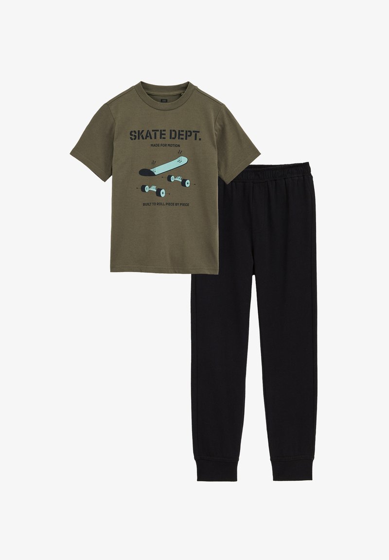 Maglietta di cotone verde oliva con grafica di skateboard e pantaloni con fascia elastica nera in vita. Design semplice, maniche corte e vestibilità regolare.