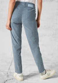 Svetle modré manšestrové kalhoty se slim fit, mají dvě zadní kapsy a tkanou etiketu na pase, v kombinaci s krémovými teniskami.