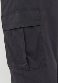 Pantaloni cargo in tessuto grigio scuro, caratterizzati da una grande tasca laterale e dettagli cuciti. Texture morbida con un design funzionale.
