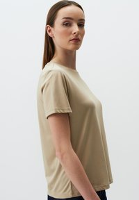 T-shirt beige a maniche corte con scollo rotondo, realizzato in tessuto morbido, caratterizzato da una vestibilità comoda e dettagli di cucitura delicati.