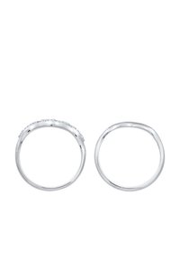 Deux anneaux en argent exposés côte à côte. L'un présente une rangée de petites pierres claires sur le dessus, tandis que l'autre a un design de bande lisse et simple.