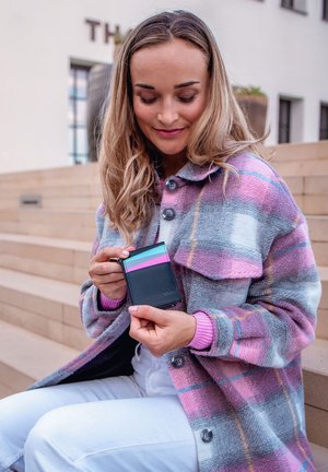 Black cardholder with turquoise, pink, and gray horizontal stripes. Smooth texture, compact design, displayed in a person's hand against a soft backdrop.