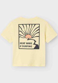Camiseta de algodón amarilla con un estampado gráfico de un sol, olas y una silueta con el texto "OLA DE CALOR // SURF" en negro.