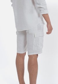 Witte linnen cargo shorts met twee grote zijzakken, een relaxte pasvorm, omgeslagen boorden en een zachte, textuurfinish.