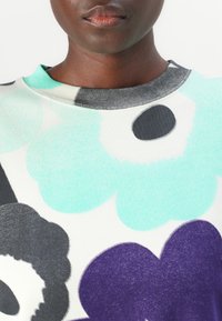 Svetre s okrúhlym výstrihom, so smerom na multicolor kvetinovým vzorom v mentolovo zelenej, čiernej a fialovej farbe na bielom pozadí.