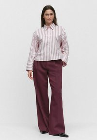Striped pink button-up shirt with wide cuffs, paired with burgundy wide-leg pants and black pointed shoes. Simple, tailored design.