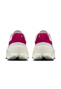 Un paio di scarpe da ginnastica bianche e magenta viste da dietro, con suole spesse e testurizzate e loghi del marchio visibili sui talloni.