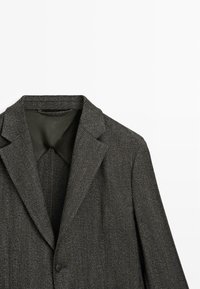 Blazer grigio con motivo a spina di pesce, rever a lancia, chiusura con un solo bottone e fodera liscia, caratterizzato da una vestibilità sagomata e una texture sottile.