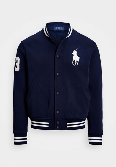 Ναυτικό μπλε αθλητικό τζάκετ από βαμβακερό μείγμα, με λευκές ρίγες στον γιακά και στις μανσέτες, μπροστινές τσέπες και κεντημένο λογότυπο.