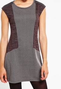 Robe sans manches avec un corps texturé gris et des panneaux latéraux bordeaux. Encolure ronde et tissu doux et lisse avec une coupe décontractée.