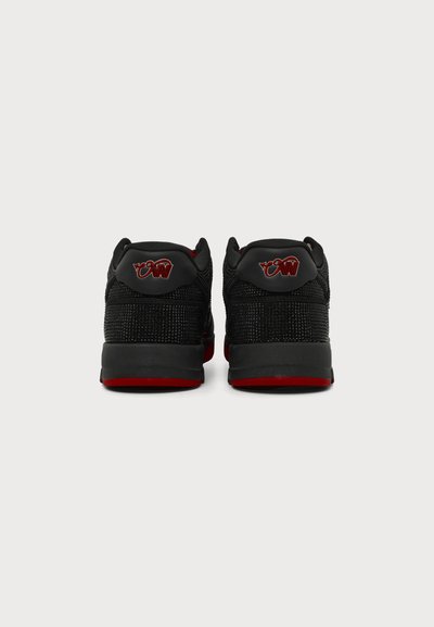 Paire de baskets noires et rouges vues de dos avec un tissu tricoté texturé et un logo rouge et noir sur la languette du talon.