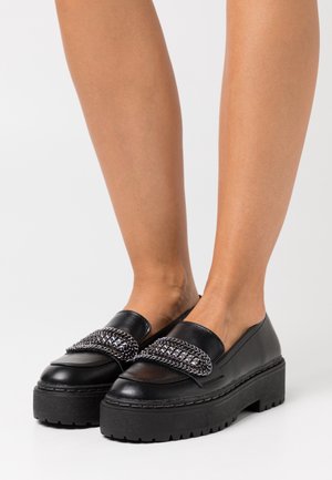 Zwarte platform loafers met een getextureerde rubberen zool, versierd met een kettingdetail over de bovenkant. Gladde leren bovenkant.