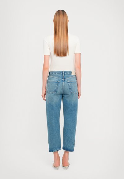 Jeans in denim azzurro chiaro con una vestibilità dritta e rilassata, design a cinque tasche e vita alta, abbinati a una semplice maglietta bianca.