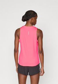 Ροζ αθλητική φανέλα με στρογγυλή λαιμόκοψη και λείο υλικό, σε συνδυασμό με μαύρο σορτς που έχει διακριτικό σχέδιο στο πλάι.