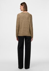 Maglione in misto lana marrone con vestibilità rilassata, scollatura a girocollo e maniche lunghe, abbinato a pantaloni neri a gamba larga. Design semplice e testurizzato.