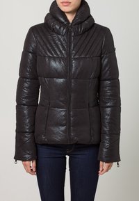 Giacca imbottita nera con finitura lucida, caratterizzata da motivi a rombi diagonali, colletto alto e tasche con zip.