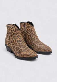 Bottines en suède imprimé léopard, dotées d'une fermeture éclair sur le côté, d'un bout pointu et d'un petit talon empilé. Schéma de couleurs marron et noir.