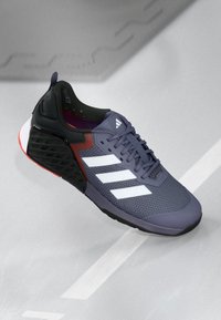 Purple and black athletic shoe with mesh upper, three white stripes, textured heel, and gray-red accents. Features a cushioned sole.