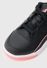 Schwarzer Sneaker aus perforiertem Leder, mit strukturierter Schnürsenkelpartie, weißer Zwischensohle und pinkfarbener Gummisohle. Mit einem pinkfarbenen Logoakzent an der Seite.