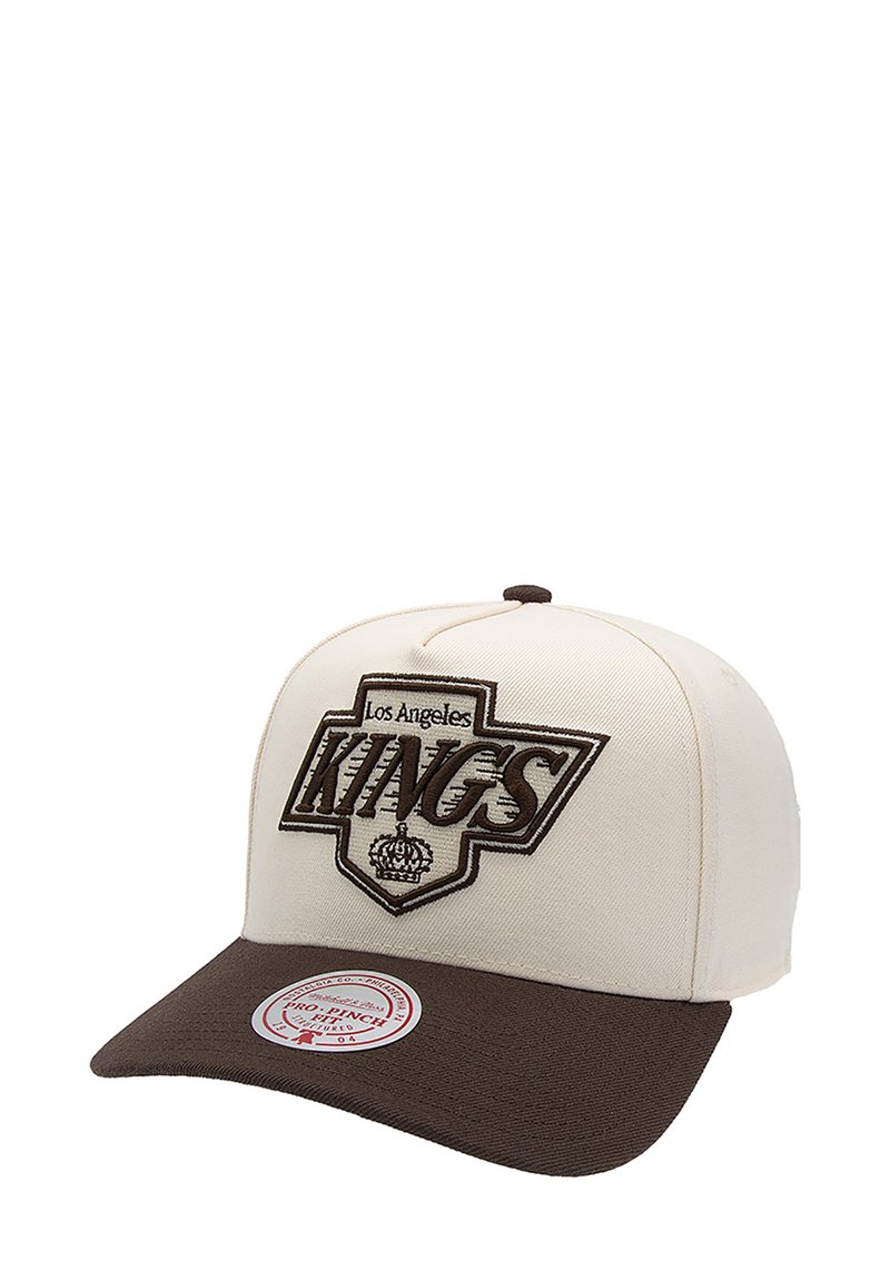 Casquette crème avec une visière marron, arborant "Los Angeles KINGS" brodé en marron et un motif de couronne. Grand logo circulaire de la marque sur la visière.