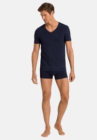 Námořnicky modré tričko s V výstřihem a přiléhavé šortky z hladkého materiálu, s krátkými rukávy a malou náprsní kapsou.