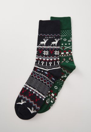 Pair of socks: one navy with white, red, and blue patterns, including reindeer; the other green with red and white geometric designs.