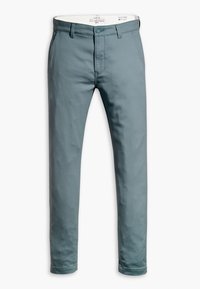 Slim-fit chinos i dämpad teal med en mjuk bomullstyg. Har en knappstängning, bältesloopar och framfickor. Ren, minimal design.