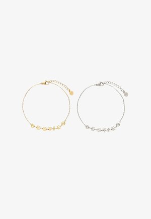 Gold- und Silberkettchen-Armbänder, jeweils mit Buchstabenanhängern, die "BESTIES" buchstabieren, und verstellbaren Verschlüssen mit kleinen runden Tags.