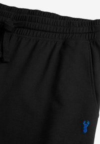 Sorte sweatpants med elastisk talje og snor. Har et lille broderet blålodde logo på underbenet. Glat tekstur.