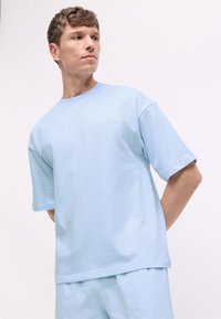 Heledad sinine lühikeste varrukatega t-särk, mis on valmistatud pehmest puuvillast. T-särk on lõdva lõikega ja sellel on rindkeres peen Calvin Klein logo.