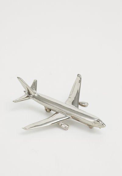 Avionetă de model strălucitor, argintie, cu două motoare, wingleți și un stabilizator, expusă pe o suprafață albă simplă.