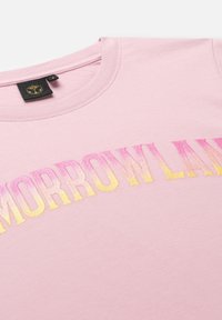 Roze t-shirt met korte mouwen en een ronde hals. Voorzien van de opdruk "TOMORROWLAND" in gradient kleuren van roze naar geel, met een zachte textuur.