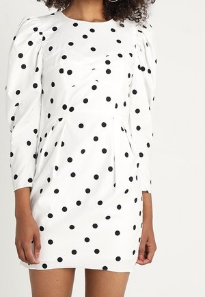 Weißes Kleid mit schwarzen Polka-Dots, langen Puffärmeln, tailliertem Oberteil, betonter Taille und leicht ausgestelltem Rock.