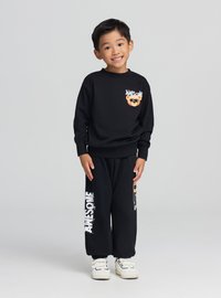 Czarny zestaw z bluzą i spodniami z grafiką niedźwiedzia na piersi oraz napisem "AWESOME" na nogawkach, do tego białe trampki.