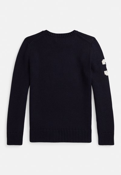 Tamsiai mėlynas megztinis su apvalia apykakle, ilgomis rankovėmis ir ribuotais rankogaliais. Kairėje rankovėje baltas skaitmeninis detalė. Megztas audinys.